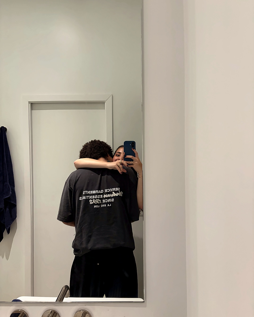 A bathroom mirror, two people holding each other.