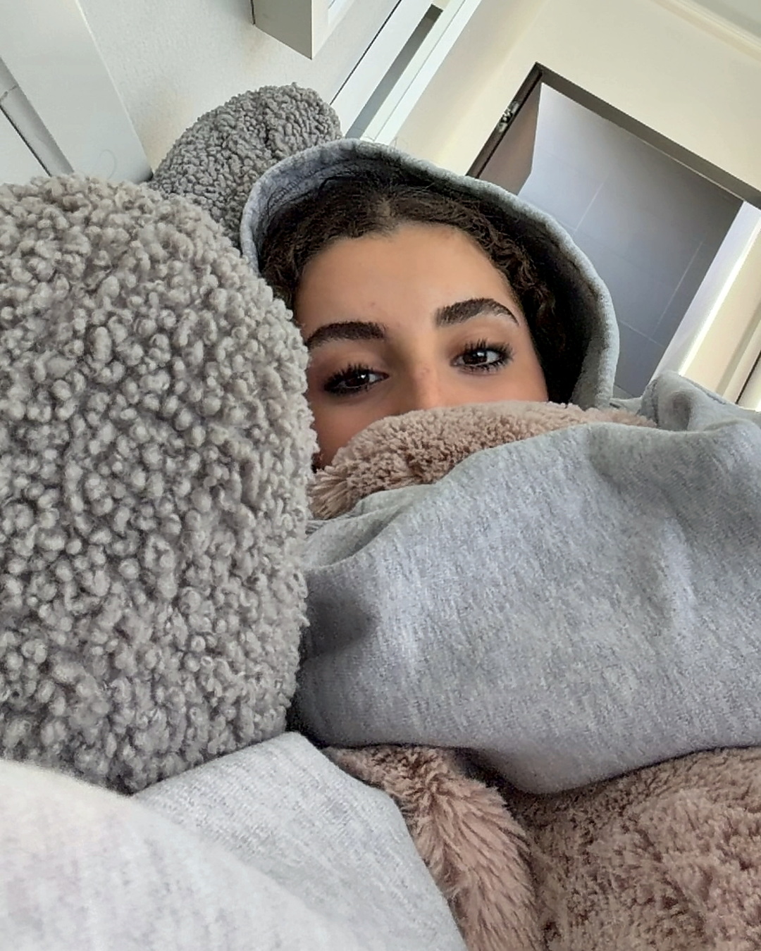 Elena in bed, peeking out from a teddy and pink blanket.