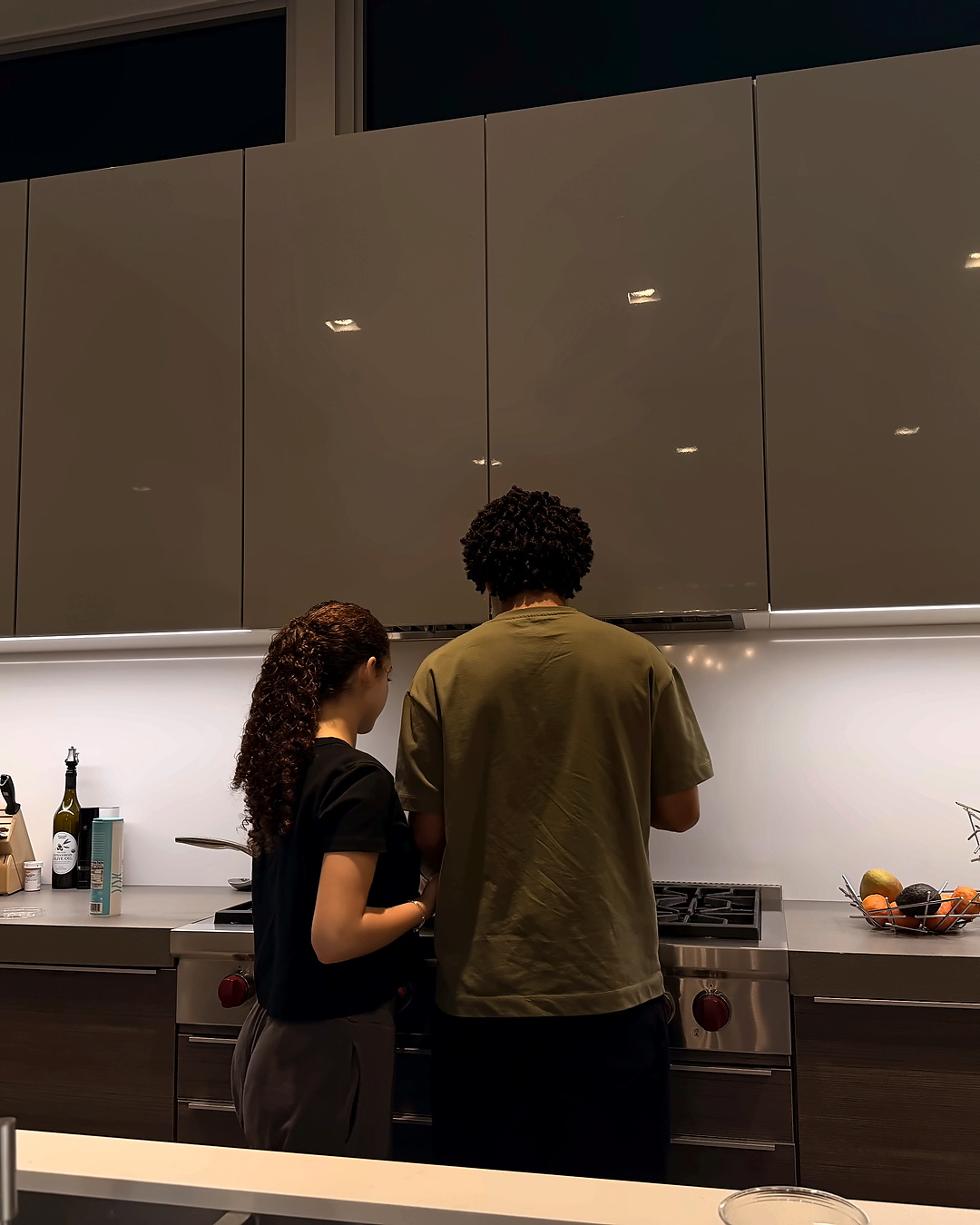 Two backs at a stove.