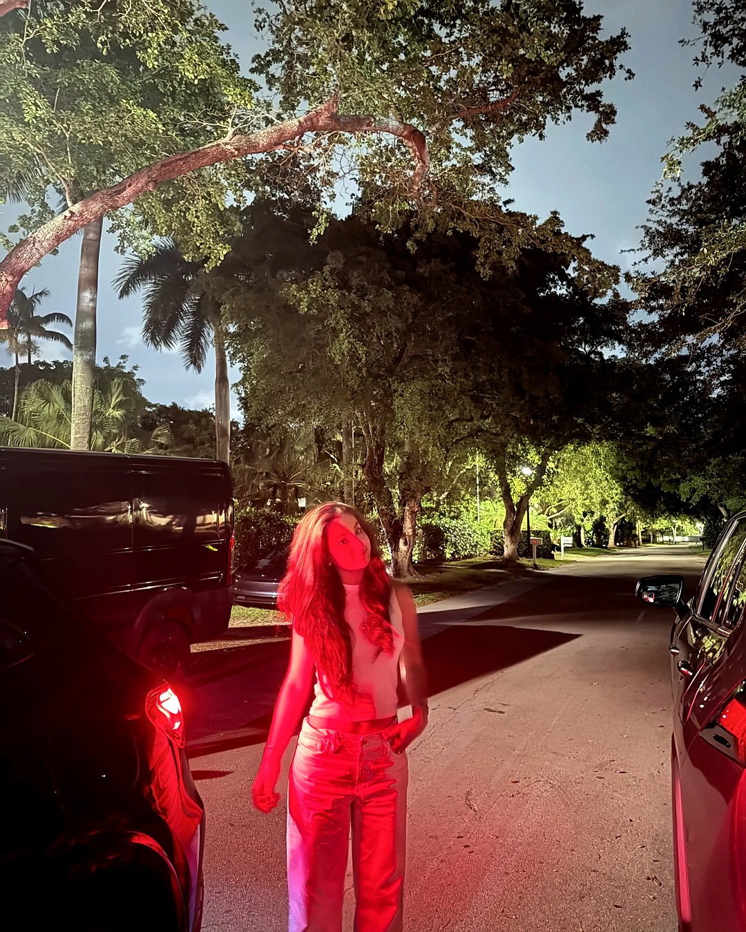 Elena under red light on a Miami street at dusk.