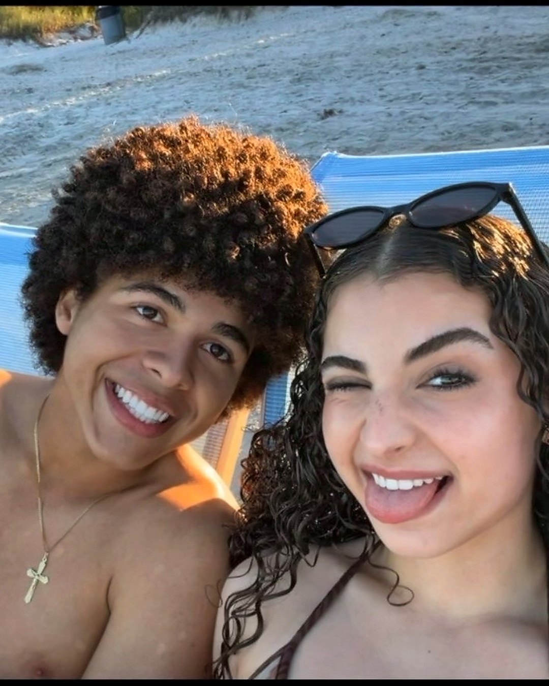 At the beach in golden hour, both smiling at the camera.